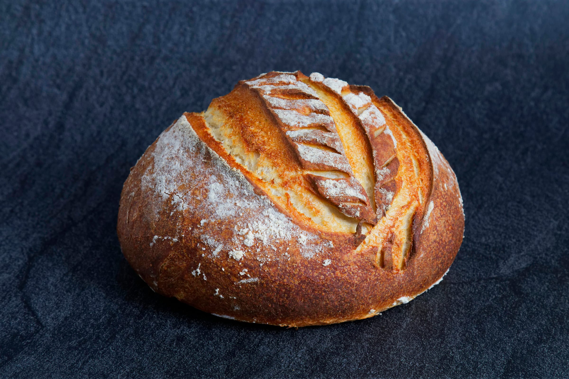 A rustic sourdough loaf on a dark wooden surface