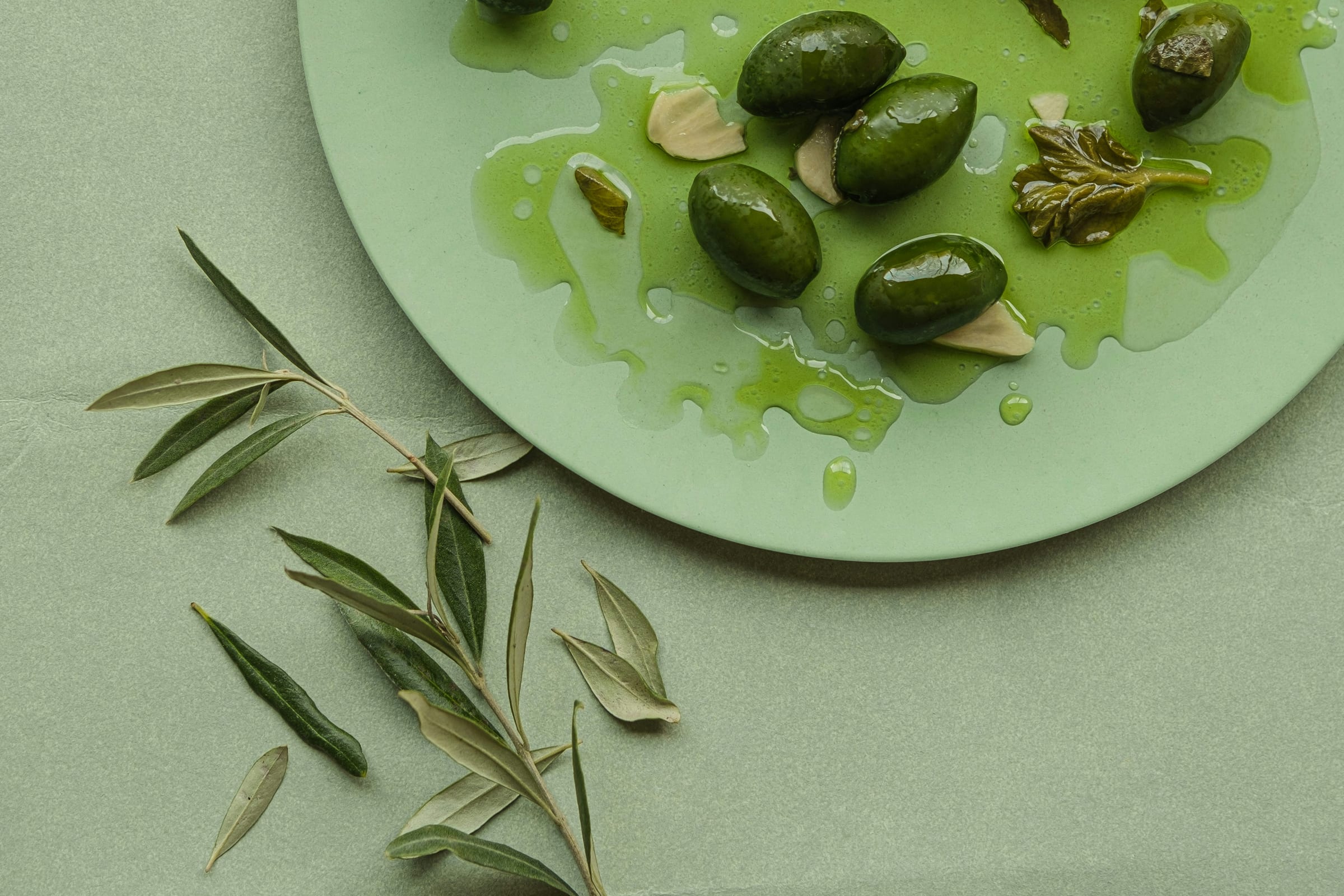 Green olives with rosemary and garlic on a plate